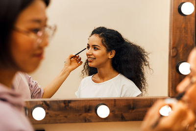 Artist doing make-up of woman in studio