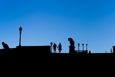 Silhouette people against clear blue sky 
