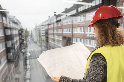 Rear view of woman with umbrella at construction site