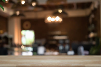 Defocused image of illuminated lights on table at restaurant