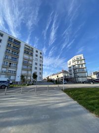 Road by buildings against sky in city