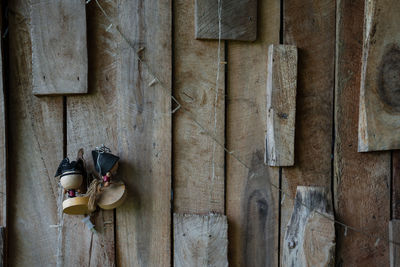Close-up of shoes hanging on wood against wall