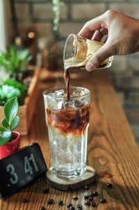 Midsection of woman pouring drink in glass on table