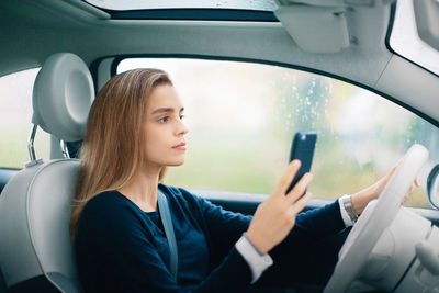 Woman using mobile phone while sitting in car