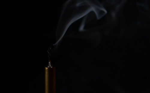 Close-up of lit candle against black background