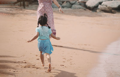 Full length of girl running on sand at beach