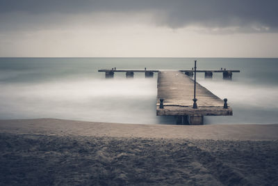 Sandy sea beach with old ruin wood pier in long exposure