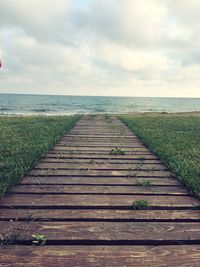 Boardwalk amidst sea against sky