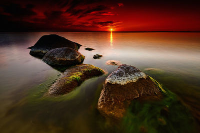 View of rocks in sea during sunset