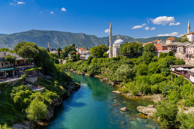 Buildings by river against sky