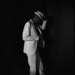 Side view of man standing against black background