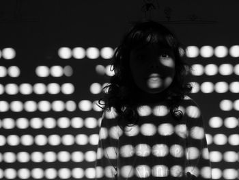 Portrait of girl standing against wall in darkroom