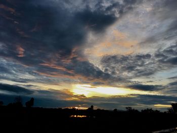 Silhouette landscape against dramatic sky during sunset