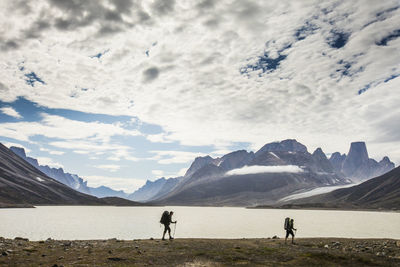 People standing on snow covered land against sky