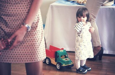 Cute baby girl standing amidst women in restaurant