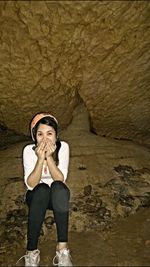 Portrait of young woman with hands covering mouth in cave