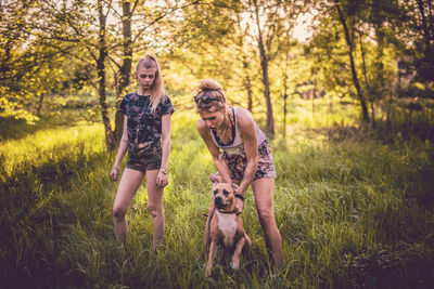 Women playing with dog on grassy field