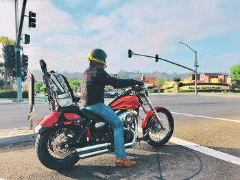 Man riding motorcycle on road against sky