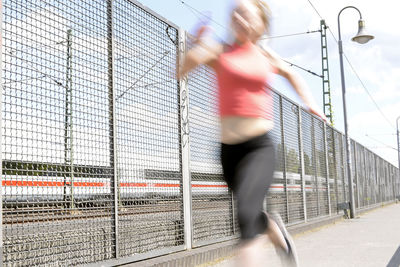 Blurred image of woman running by fence