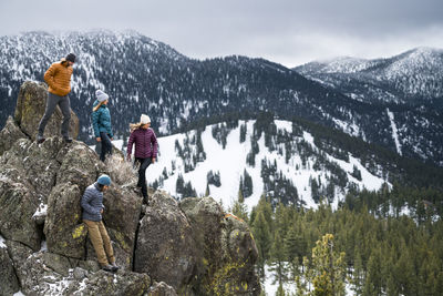 People on rocks against mountains during winter