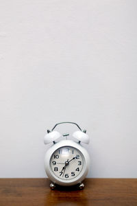 Close-up of clock on table against wall