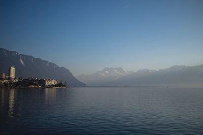 Scenic view of lake and mountains against clear blue sky