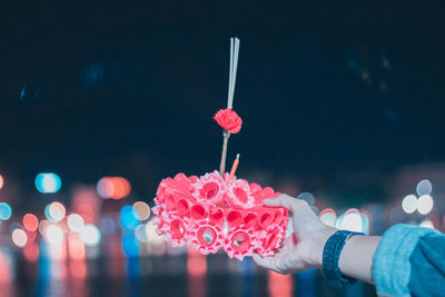 Cropped hand of man holding decoration with incense at night