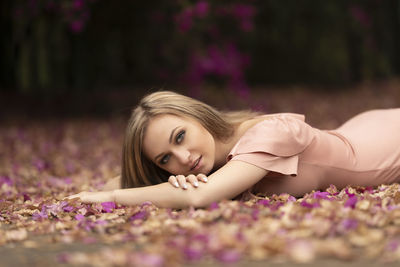 Portrait of woman lying on road amidst petals