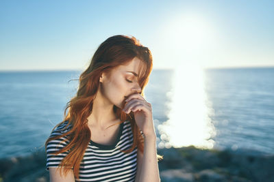 Beautiful young woman at beach against sky