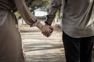 Midsection of couple holding hands