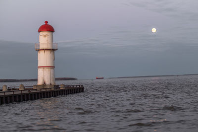 Lighthouse by sea against sky