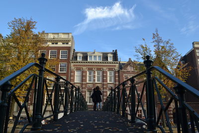 Man standing by building against sky