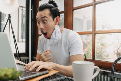 Mid adult man using mobile phone while sitting on table