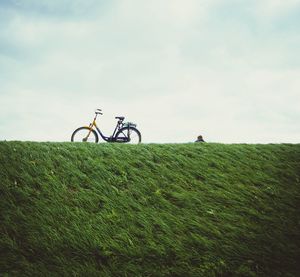 Grassy field against cloudy sky