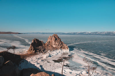 Scenic view of sea and mountains against clear blue sky