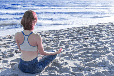 Rear view of woman sitting on beach