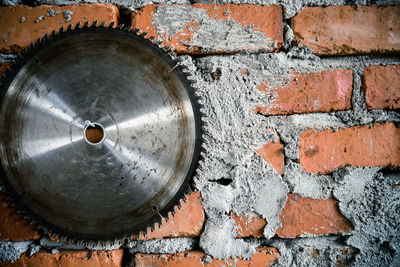 Close-up of circular saw against brick wall