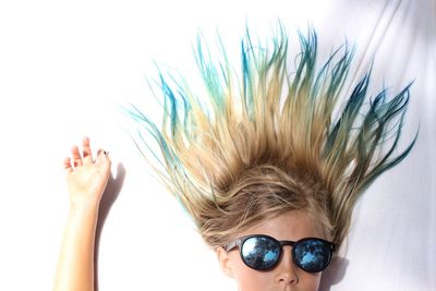 Close-up portrait of girl in sunglasses with tousled hair on bed