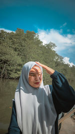 Portrait of woman standing against lake