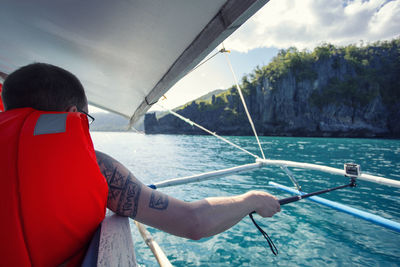 Rear view of man sailing on sea against sky