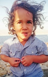 Boy buttoning shirt at beach