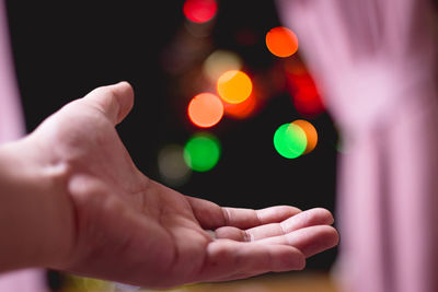 Close-up of human hand and colorful bokeh in the dark