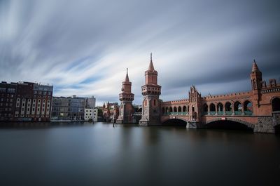 Oberbaumbrucke over spree river against cloudy sky 