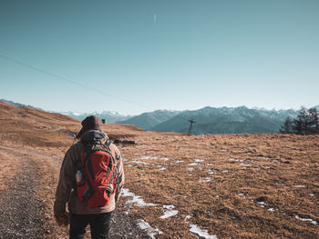 Rear view of man standing on mountain against sky