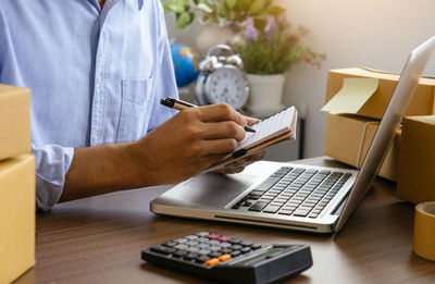 The man holding paper bills using calculator.