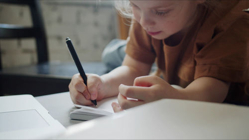 Midsection of woman writing in book at table