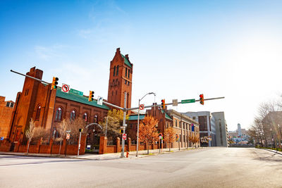 Road by buildings against sky in city