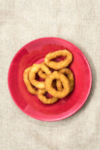 Directly above view of fresh onion rings served in plate on jute fabric