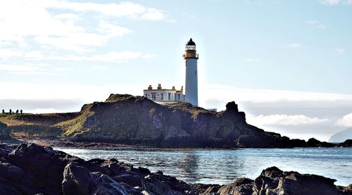 Lighthouse by sea against sky