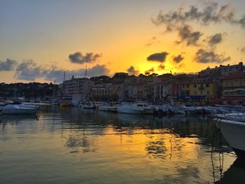 Sailboats moored in harbor against sky during sunset